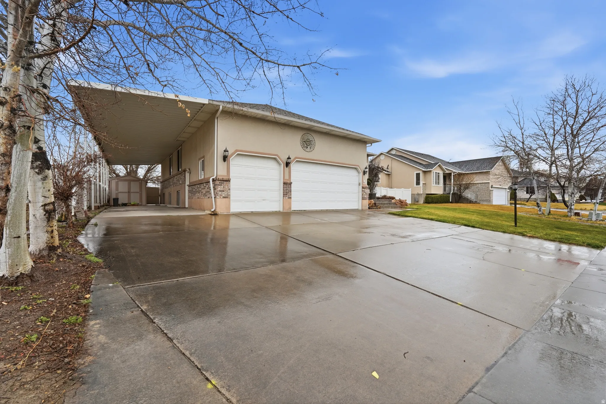 View of property exterior featuring concrete driveway, stucco siding, a garage, a lawn, and a shed