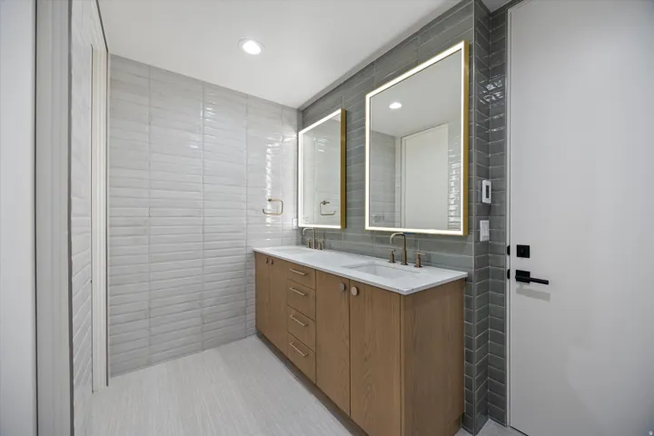 Bathroom featuring tile walls, double vanity, and recessed lighting