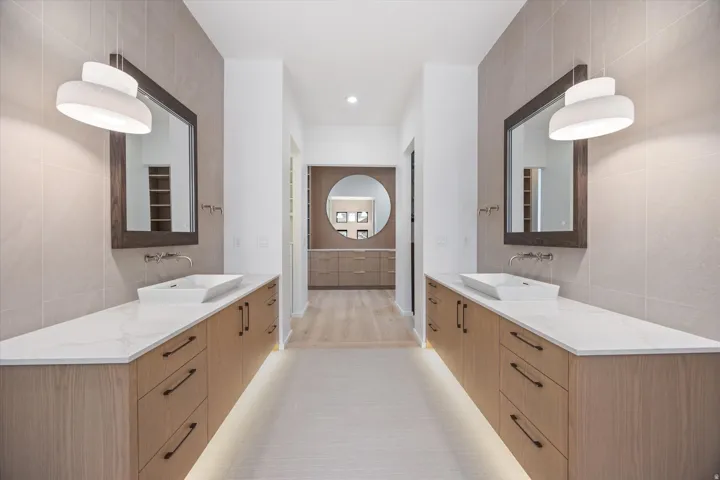 Full bath with tile walls, two vanities, and recessed lighting