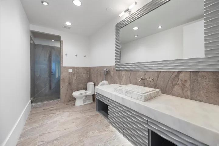 Bathroom with vanity, a marble finish shower, recessed lighting, light marble finish flooring, and tile walls