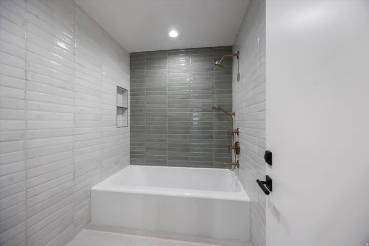 Bathroom featuring  shower combination, recessed lighting, and tile walls