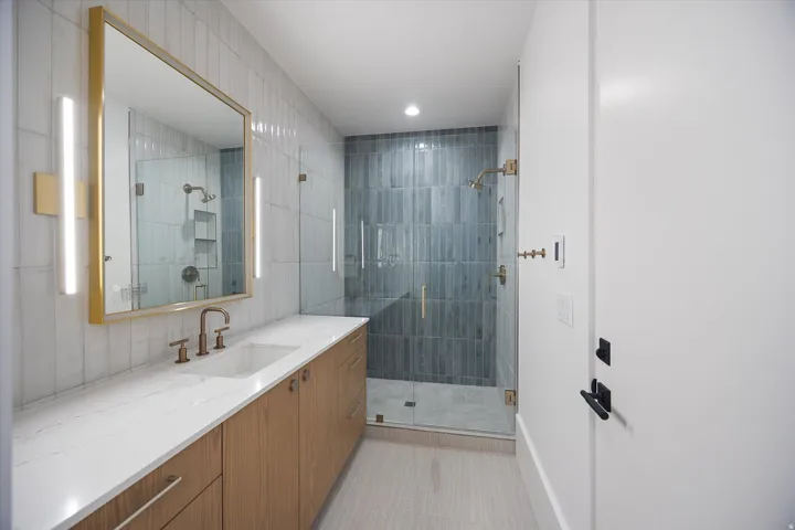 Full bathroom featuring vanity, a stall shower, recessed lighting, and tile walls