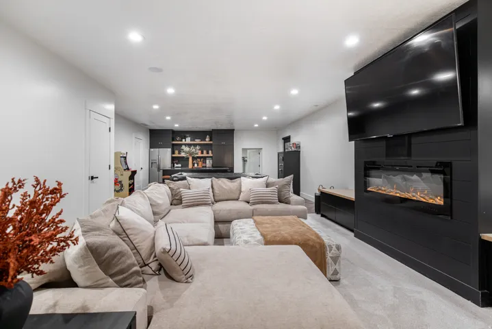 Living room featuring light colored carpet, recessed lighting, a fireplace, and bar