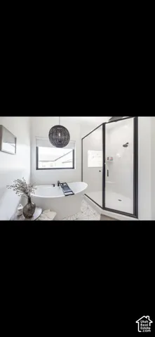Freestanding soaking tub, walk-in shower with glass enclosure, black framed window, and patterned floor tiling