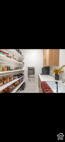 Extensive shelving, stone-finish countertop, wood-finish cabinetry, and a single-basin sink with a gold-tone faucet