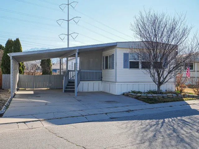 Manufactured / mobile home featuring an attached carport, concrete driveway, and a porch
