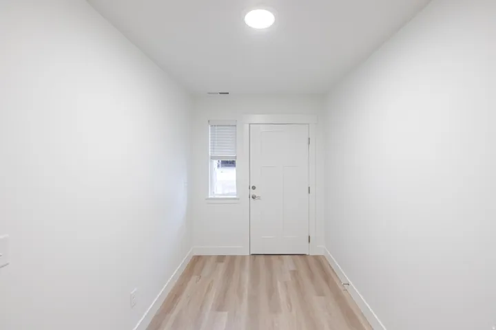 Entryway with a solid panel door, a single window with blinds, wood-finish flooring, and a flush-mount ceiling light