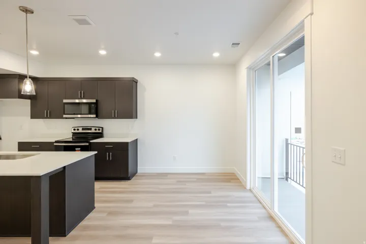 Contemporary kitchen featuring dark wood cabinetry, light countertops, stainless steel appliances, and wood-finish flooring