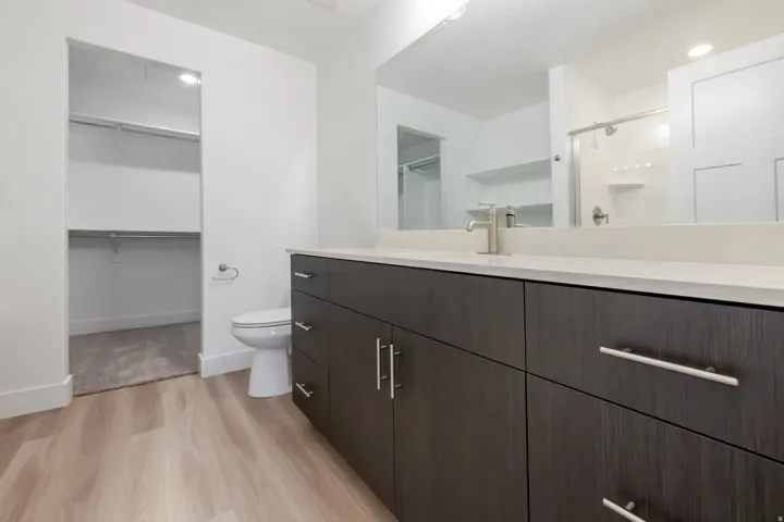 Bathroom featuring a dark wood-finish vanity with a light countertop, a rectangular sink with a brushed nickel faucet, and a large mirror