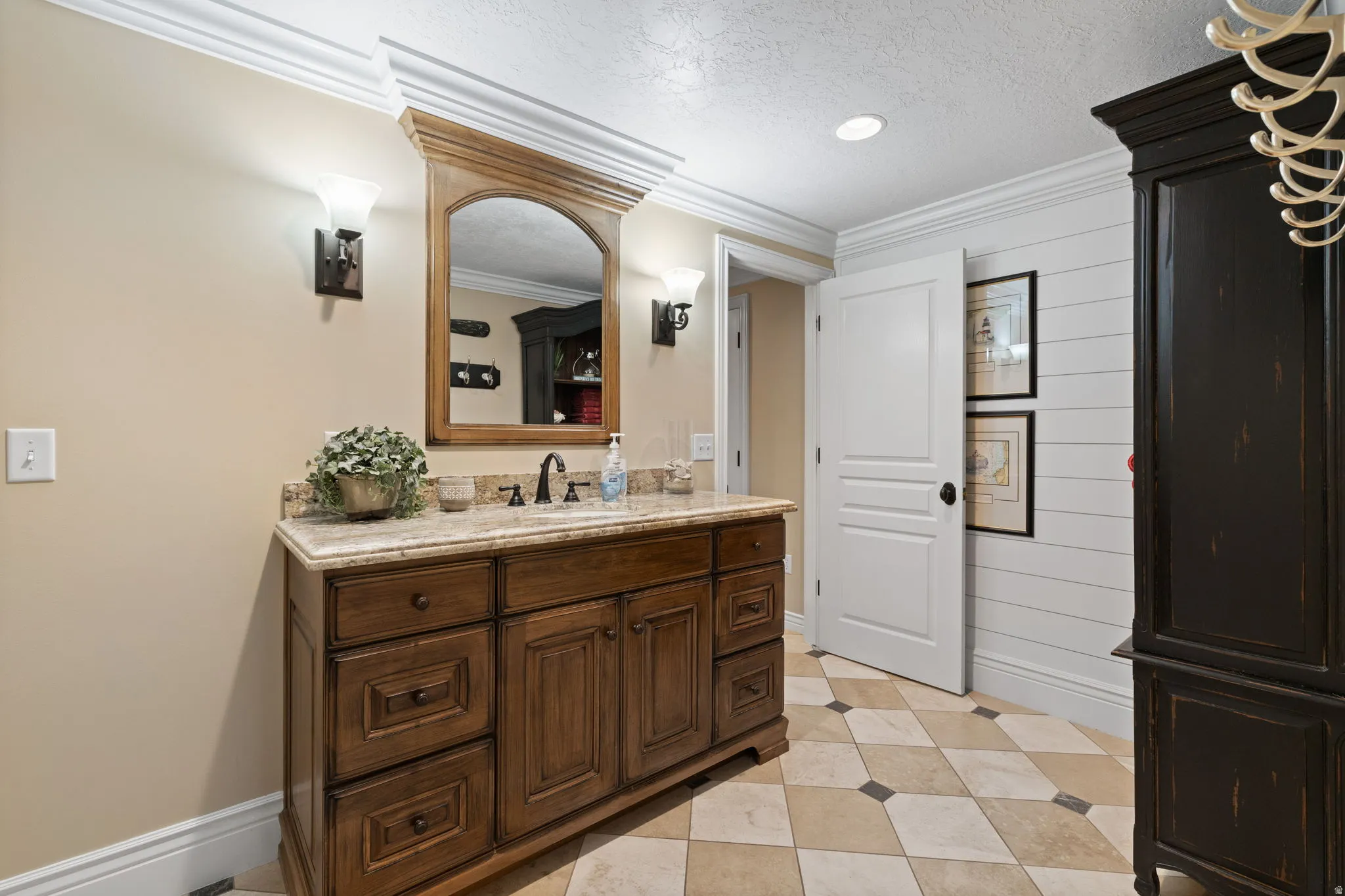 Bathroom with vanity, ornamental molding, wood walls, and a textured ceiling