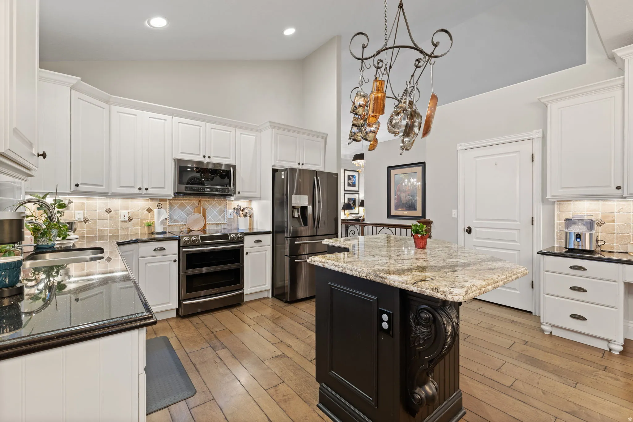 Kitchen featuring tasteful backsplash, dark stone counters, stainless steel appliances, pendant lighting, and vaulted ceiling