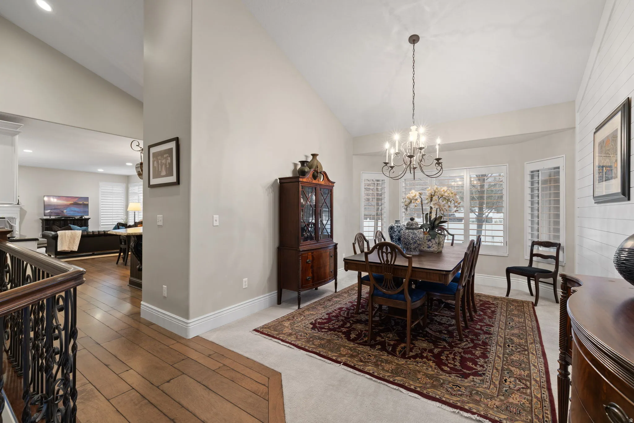 Dining area with vaulted ceiling, suspended lighting, light wood-style flooring, and light carpet