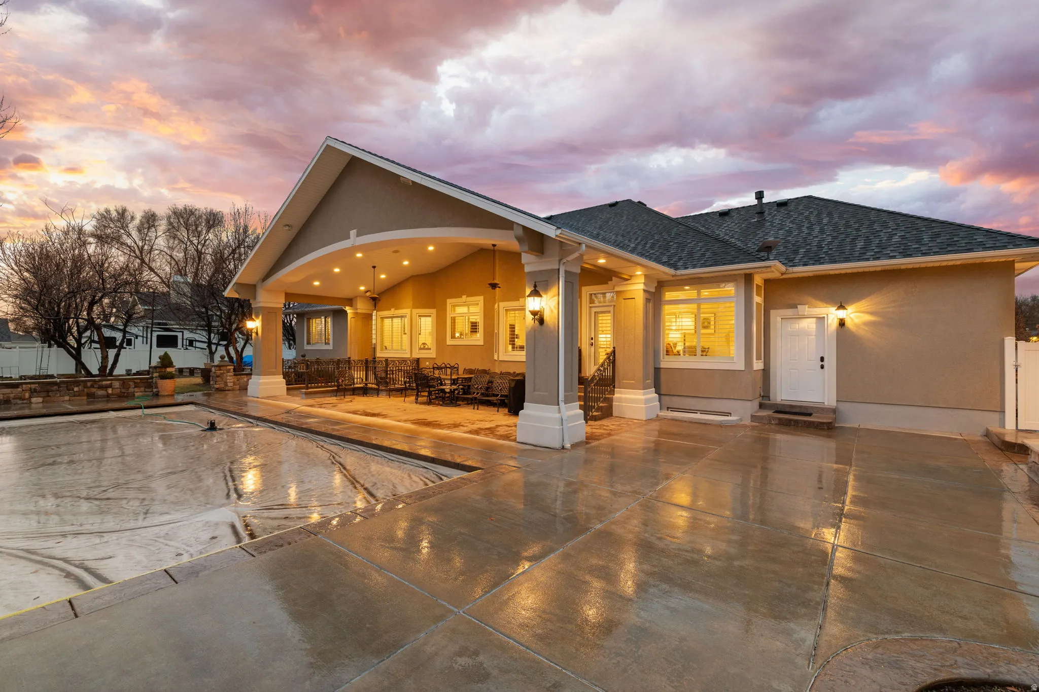 Back of property featuring a covered pool, a shingled roof, and stucco siding