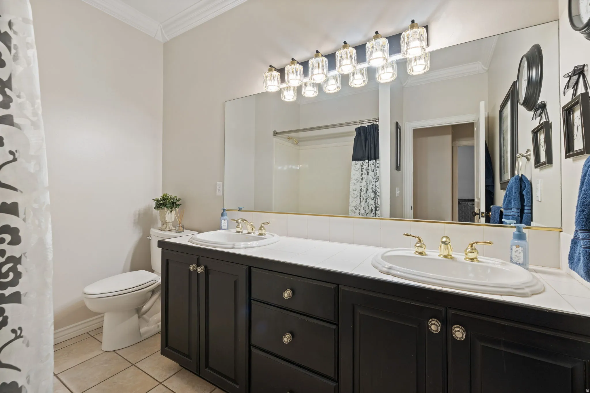 Full bathroom with crown molding, double vanity, curtained shower, and light tile patterned flooring