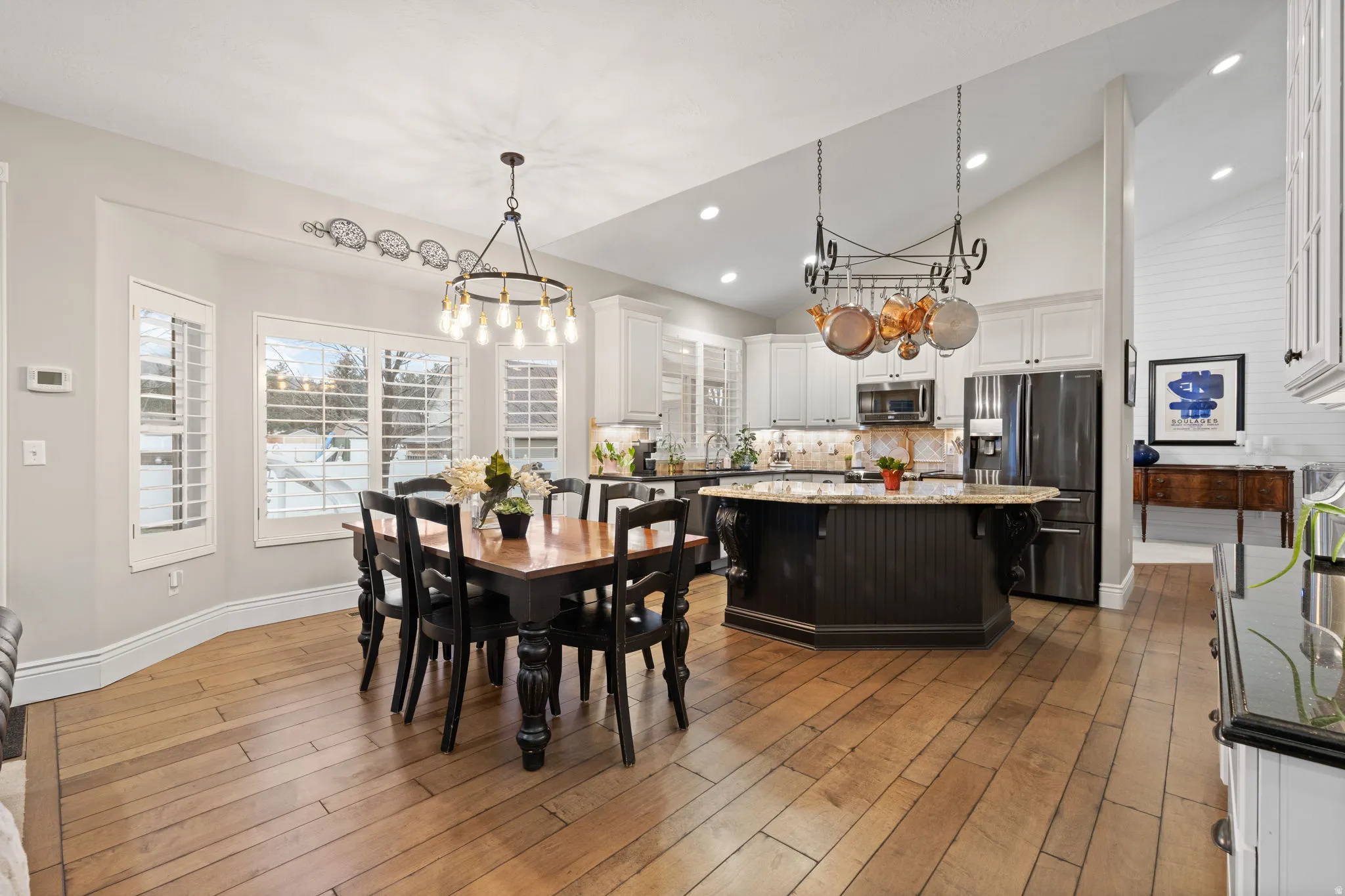 Dining area with vaulted ceiling, light wood-style flooring, and suspended lighting
