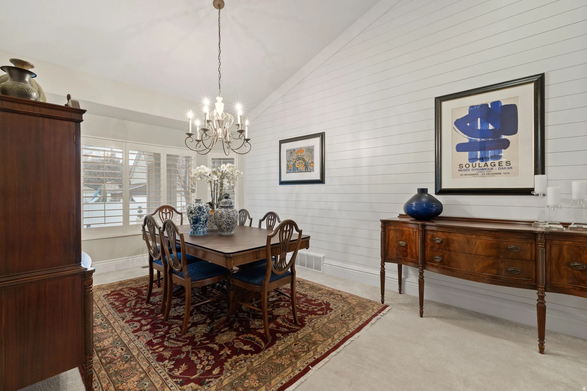Dining space featuring vaulted ceiling, hanging lights, and light colored carpet