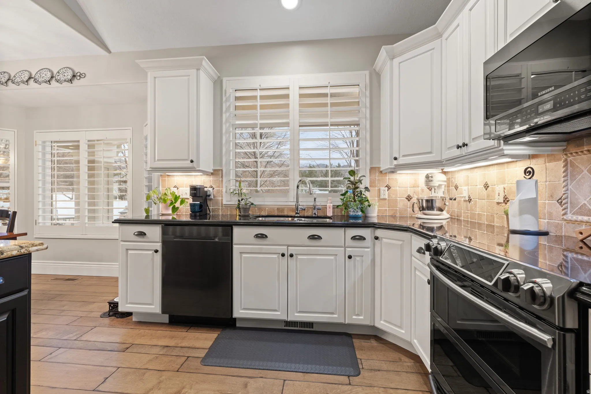 Kitchen with stainless steel microwave, double oven range, white cabinetry, light wood-type flooring, and recessed lighting