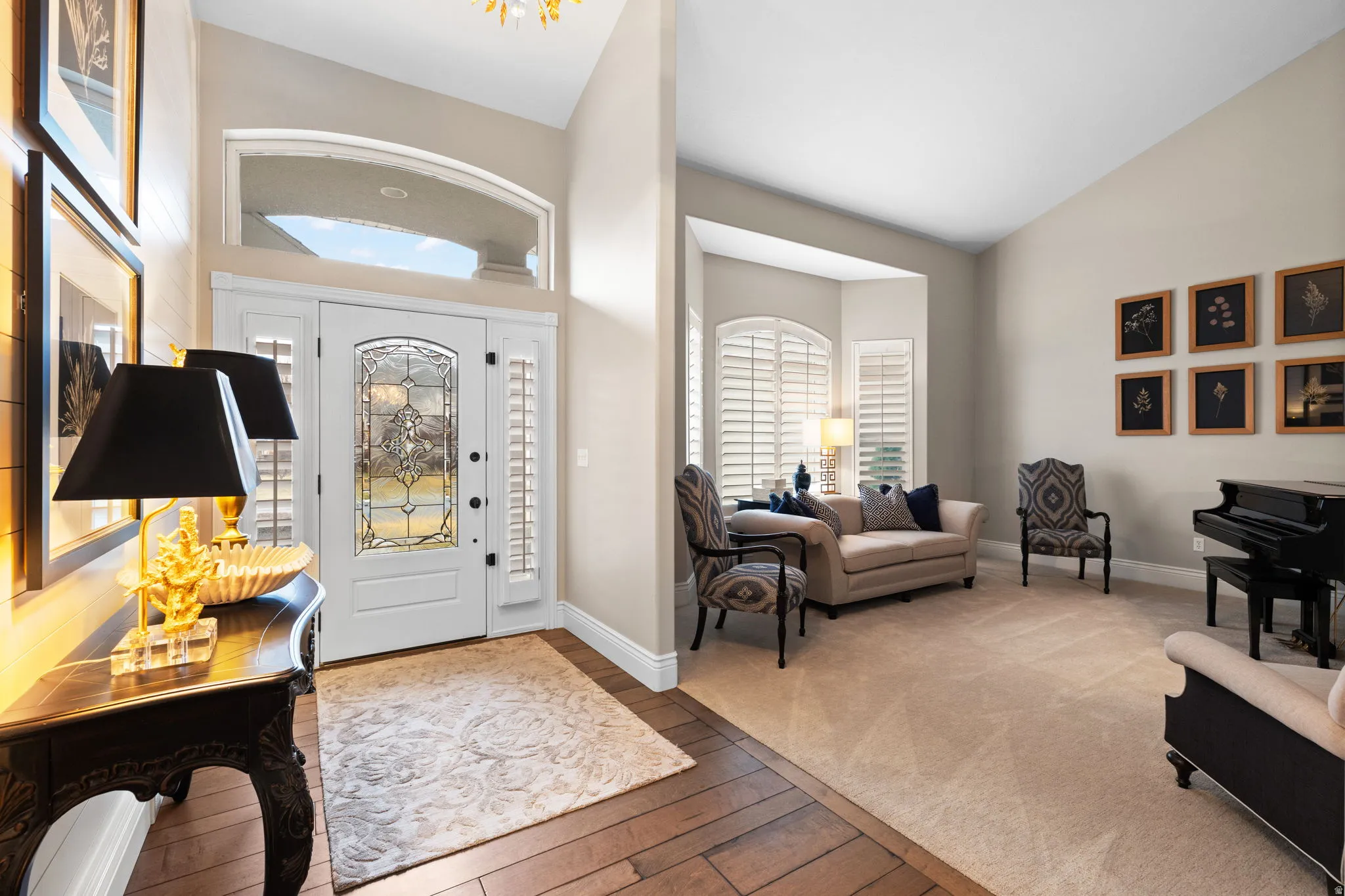 Entryway with lofted ceiling, plenty of natural light, light wood-style floors, and light colored carpet
