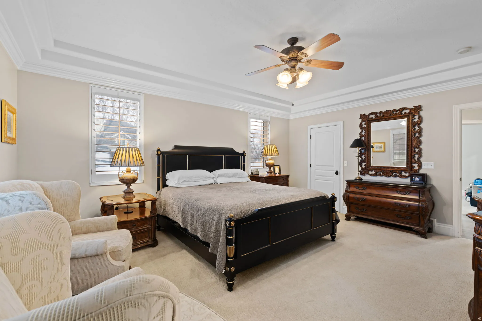 Bedroom featuring a raised ceiling, light colored carpet, a ceiling fan, and ornamental molding