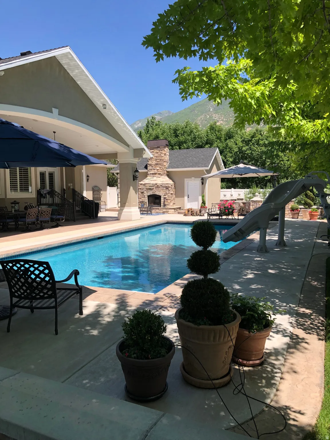 View of pool featuring patio surround, an outdoor stone fireplace, and a mountain view