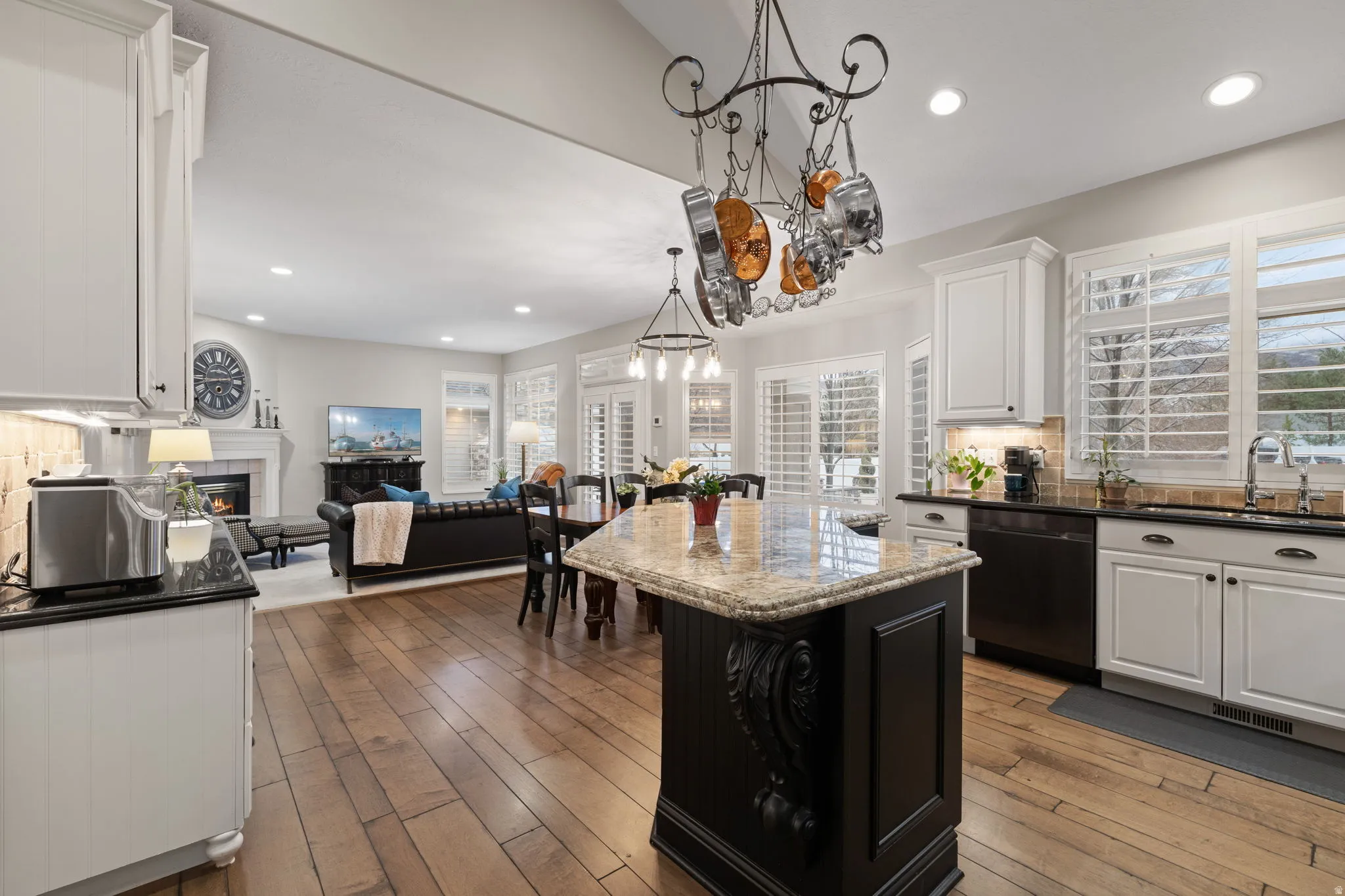 Kitchen featuring tasteful backsplash, open floor plan, dark stone countertops, a tile fireplace, and black dishwasher