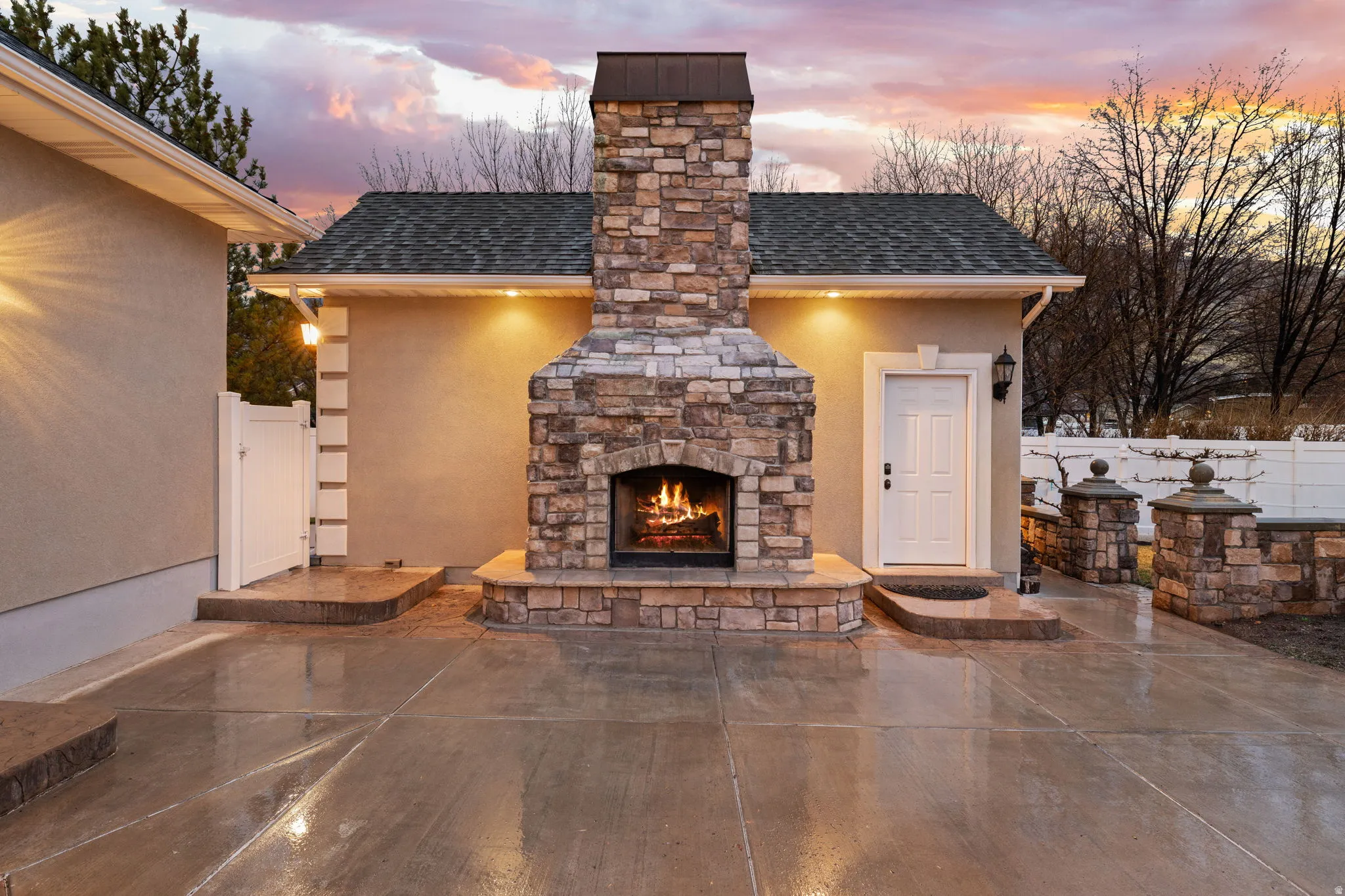 Patio terrace at dusk featuring an outdoor stone fireplace