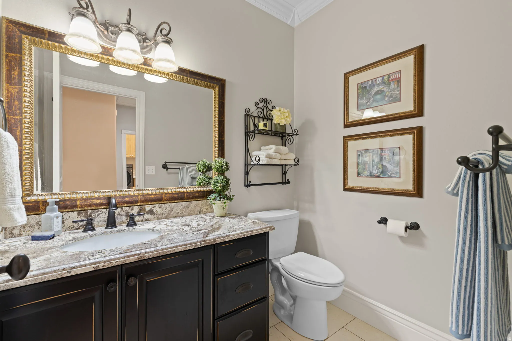 Half bathroom featuring vanity, ornamental molding, and light tile patterned floors