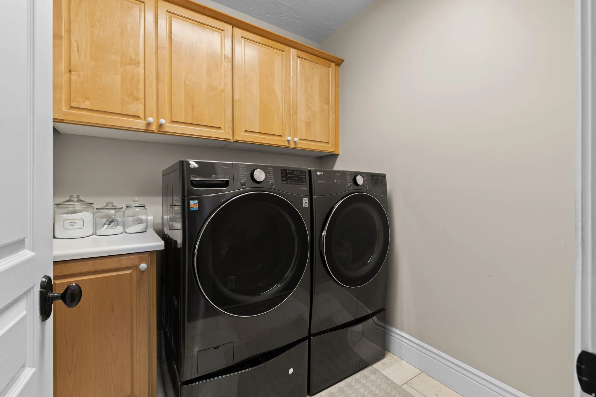 Laundry room with cabinet space, independent washer and dryer, a textured ceiling, and light tile patterned floors