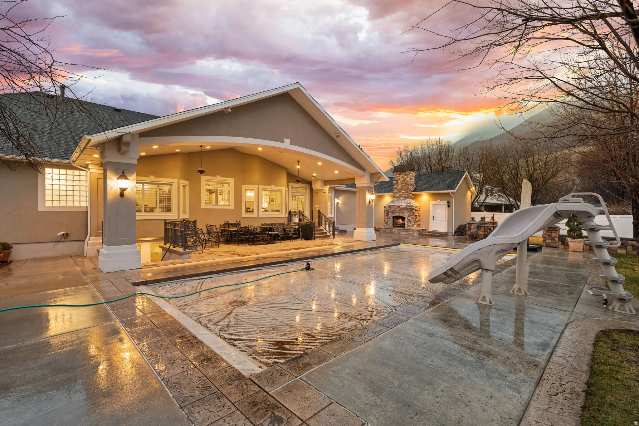 Back of house at dusk with stucco siding, a patio, and an outdoor pool