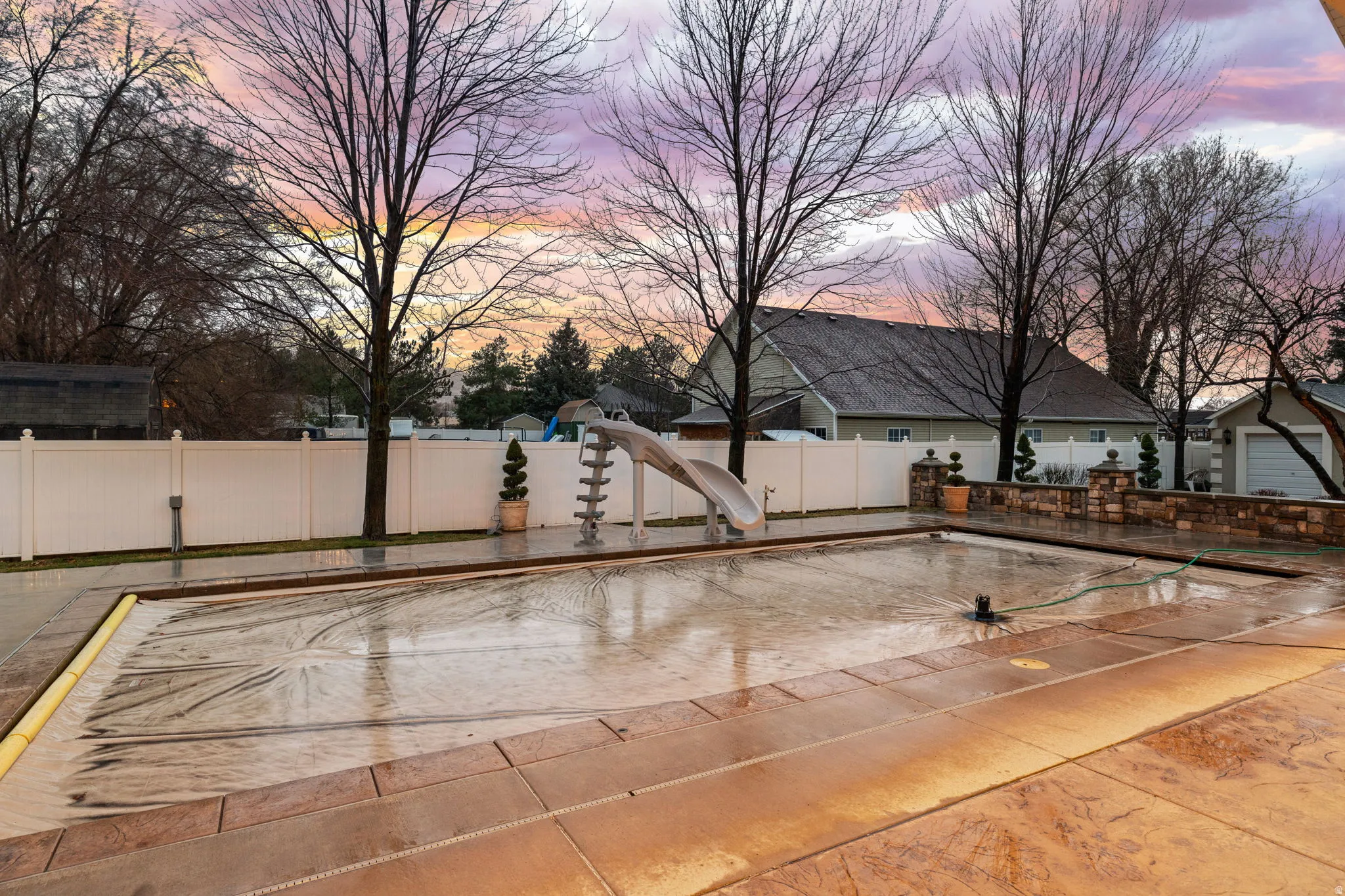 Pool at dusk with a water slide and a patio