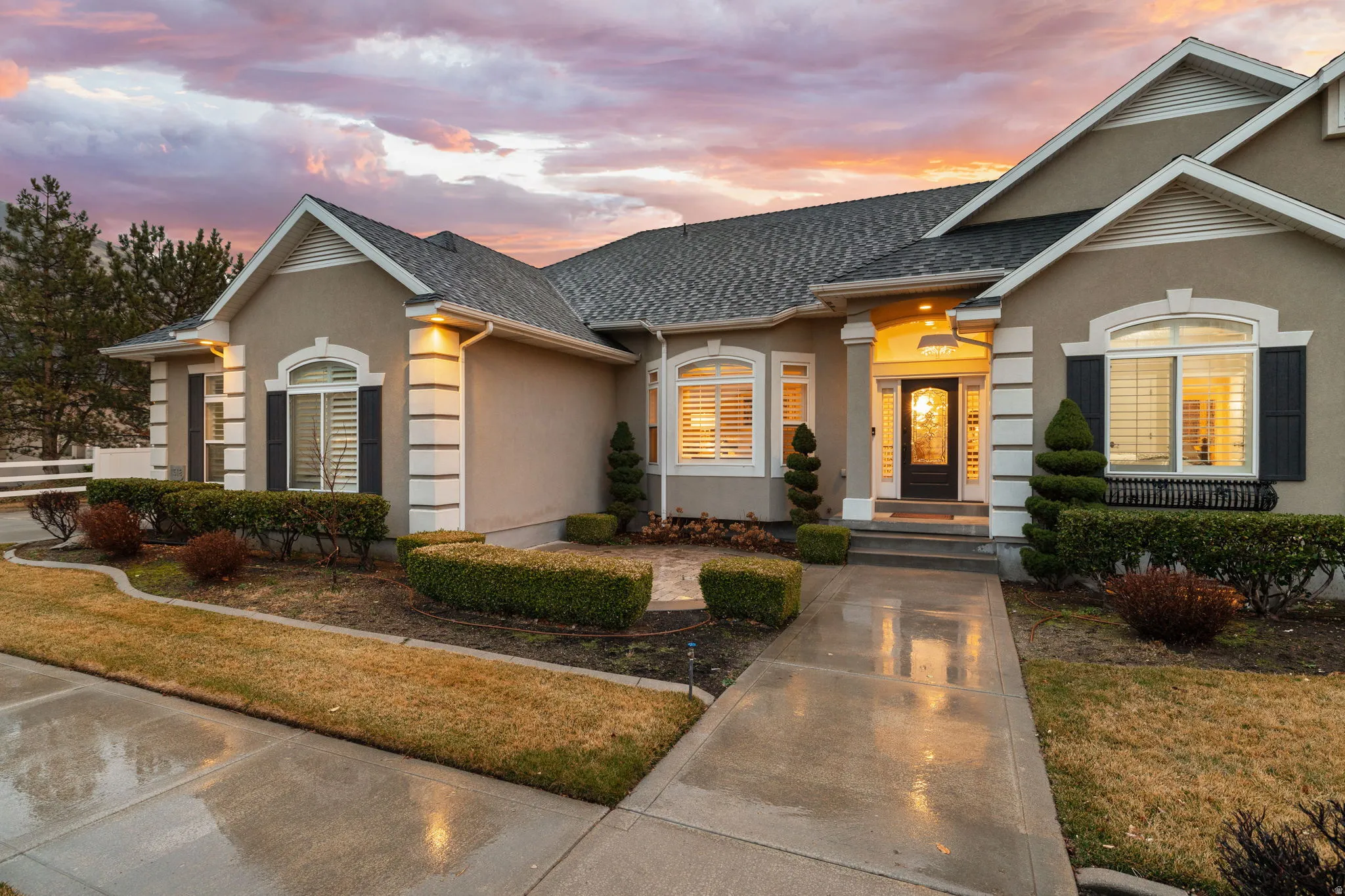 View of front facade with stucco siding, a shingled roof, and a front yard