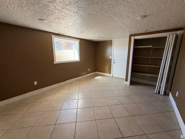 Unfurnished bedroom with a closet, a textured ceiling, and light tile patterned floors