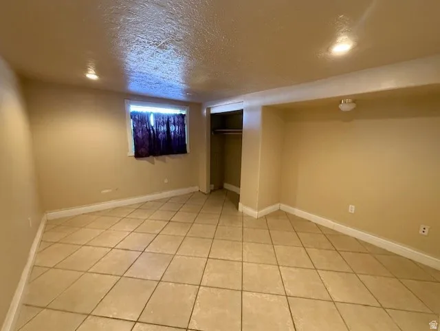 Finished basement featuring a textured ceiling and light tile patterned flooring
