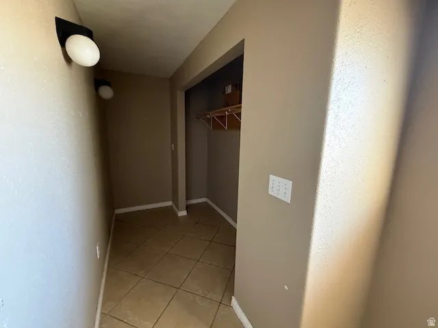 Hall featuring light tile patterned flooring and baseboards