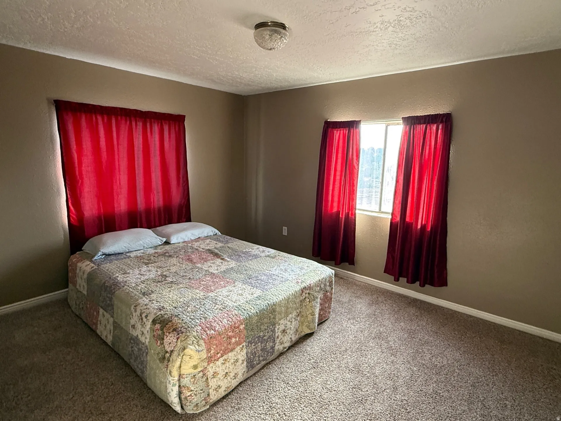 Bedroom with a textured ceiling, a textured wall, and carpet