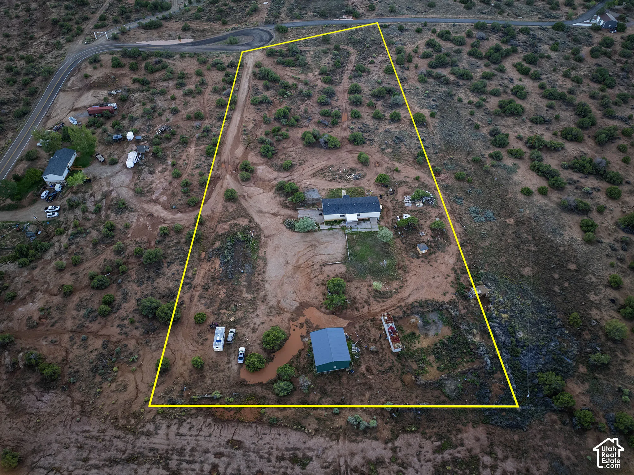 Expansive undeveloped land featuring a residential structure and a separate accessory building