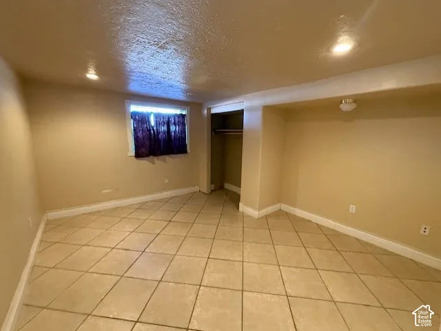 Finished basement featuring a textured ceiling and light tile patterned flooring