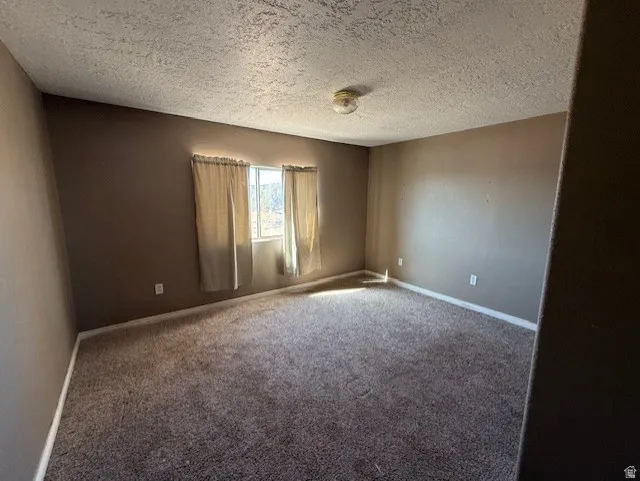 Unfurnished room featuring a textured ceiling and carpet floors