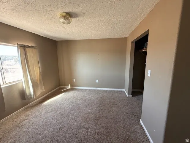 Carpeted spare room with baseboards and a textured ceiling