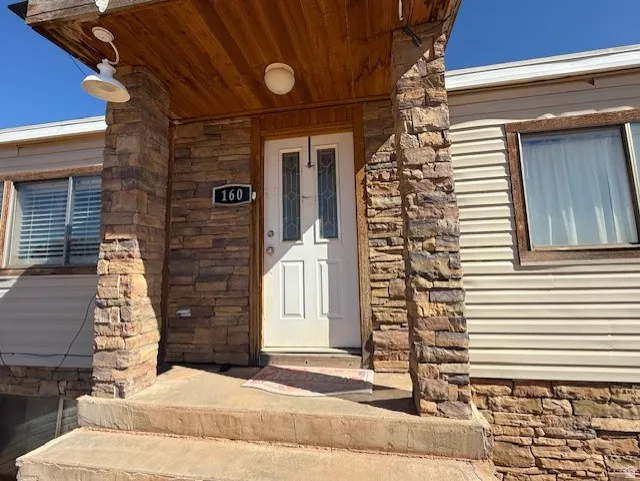 Property entrance featuring stone siding and covered porch