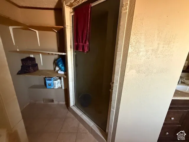 Full bath featuring light tile patterned floors, a stall shower, and vanity