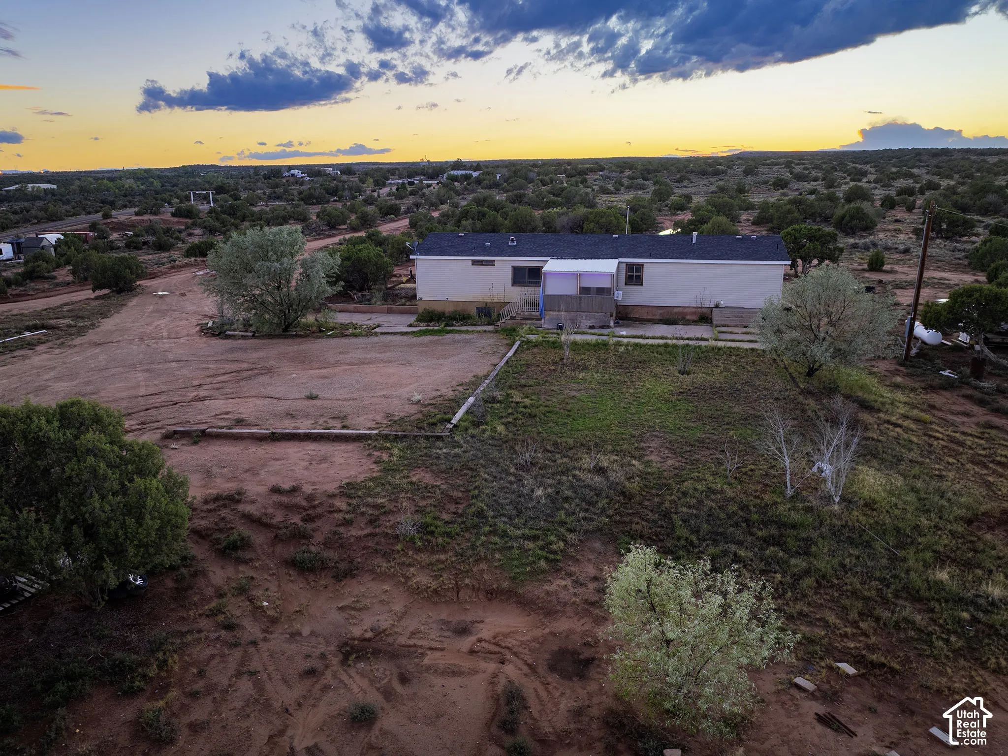 Expansive property featuring a single-story residence with a covered porch, surrounded by mature trees and natural landscaping