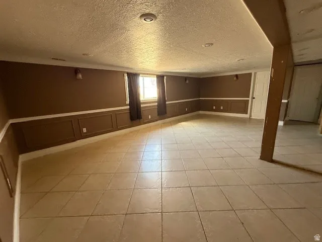 Below grade area featuring wainscoting, light tile patterned floors, and a decorative wall