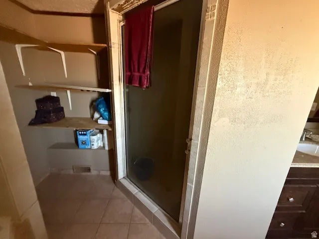Full bath featuring light tile patterned floors, a stall shower, and vanity