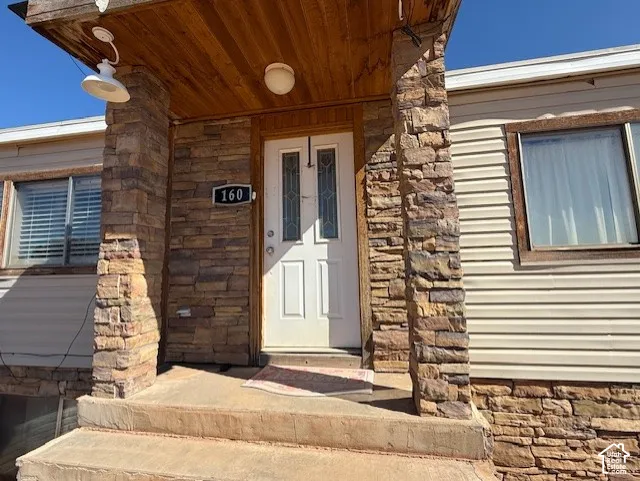 Property entrance featuring stone siding and covered porch