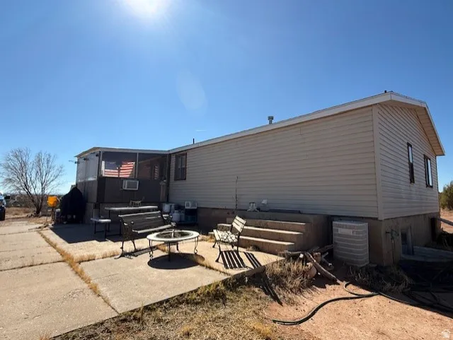 Rear view of property featuring a patio and an outdoor fire pit