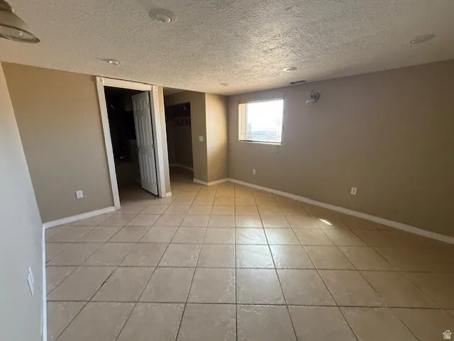 Unfurnished bedroom featuring a walk in closet, a textured ceiling, and light tile patterned floors