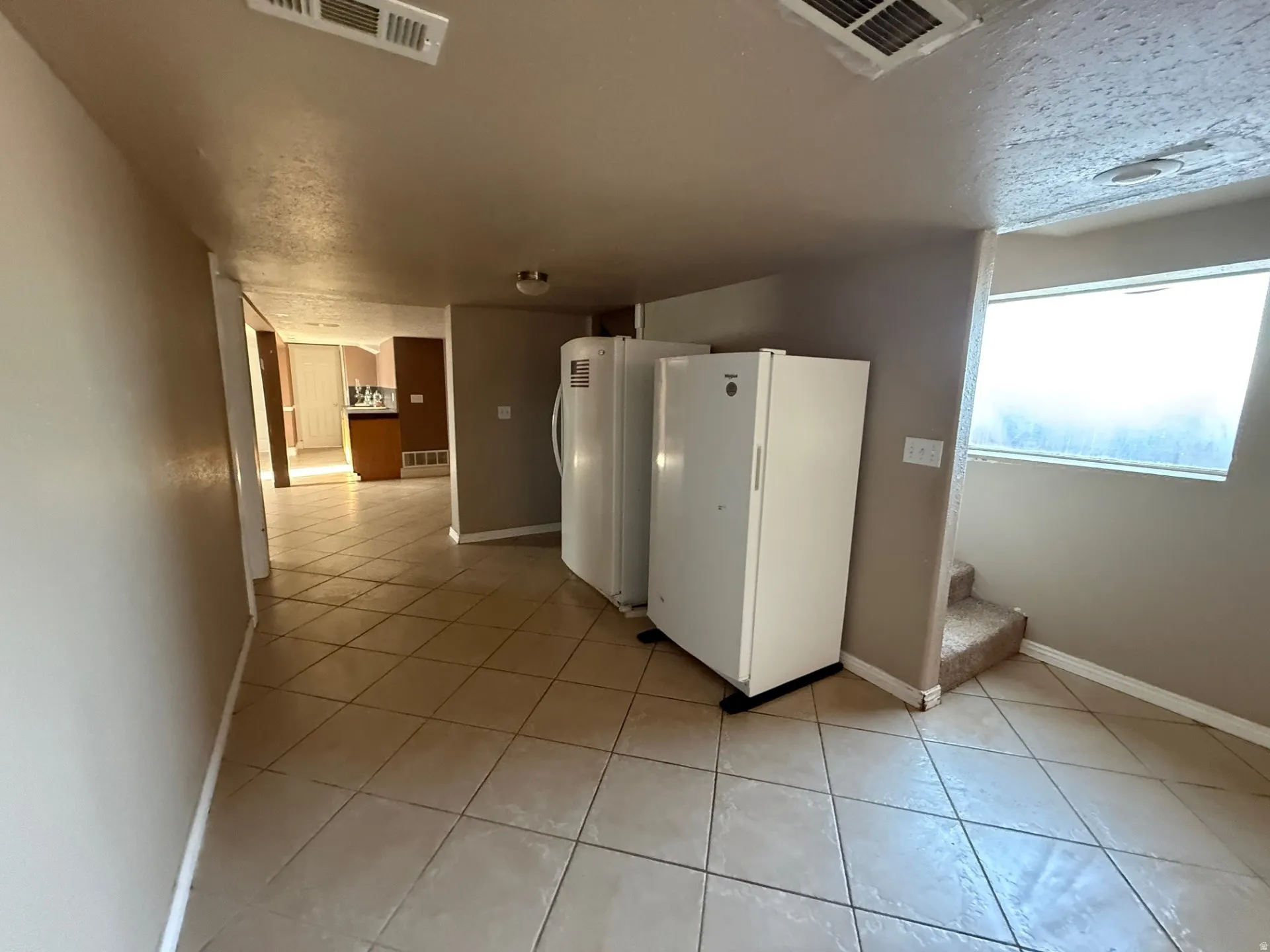 Laundry room featuring light tile patterned floors and a textured ceiling
