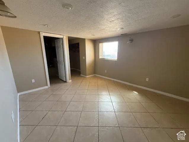 Unfurnished bedroom featuring a walk in closet, a textured ceiling, and light tile patterned floors