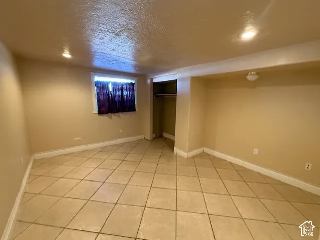 Finished basement featuring a textured ceiling and light tile patterned flooring